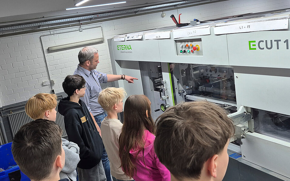 Der Abteilungsleiter erläutert die Technik beim Stanzen