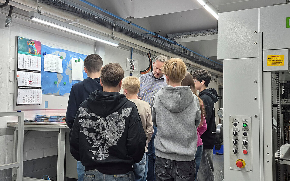 Kids neben einer große Stanzmaschine bei Kip